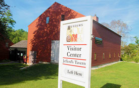 Museums of Old York exterior image of a museum visitor center sign outside of a big red museum barn