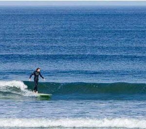 Things To Do in Maine a person surfing in the ocean, riding a wave