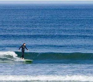 a person surfing in the ocean, riding a wave