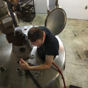 Wiggly Bridge Distillery a man climbing into a distill