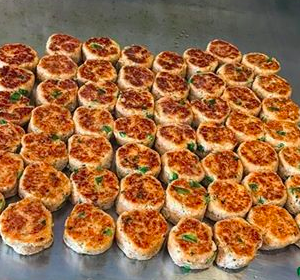 a spread of crab cakes on a table, light topped with green garnish on top