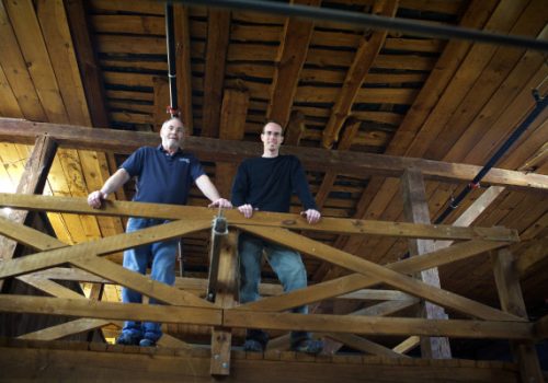 two men standing off a balcony in the distillery