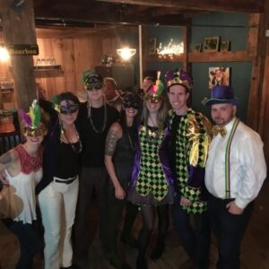 a group of 7 people dressed up in a bar for mardi gras