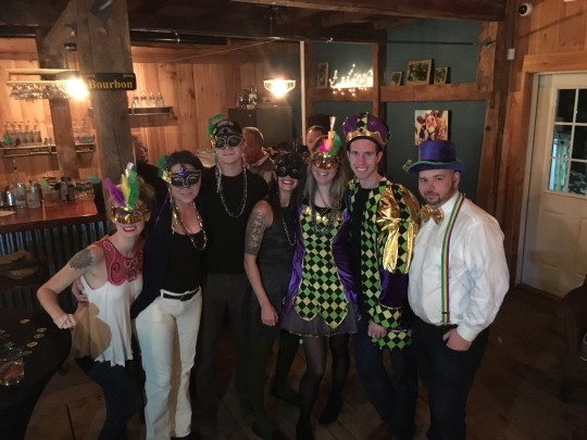 a group of 7 people dressed up in a bar for mardi gras