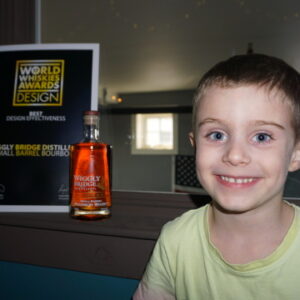 a boy in a yellow shirt smiling in front of an award