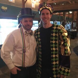 two men dressed up in mardi gras costumes smiling and posing for a photo